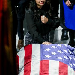 Elizabeth Romrell, wife of South Salt Lake police officer David Romrell, rests her hand on his casket at the end of his funeral at the Maverik Center in West Valley City on Wednesday, Dec. 5, 2018.
