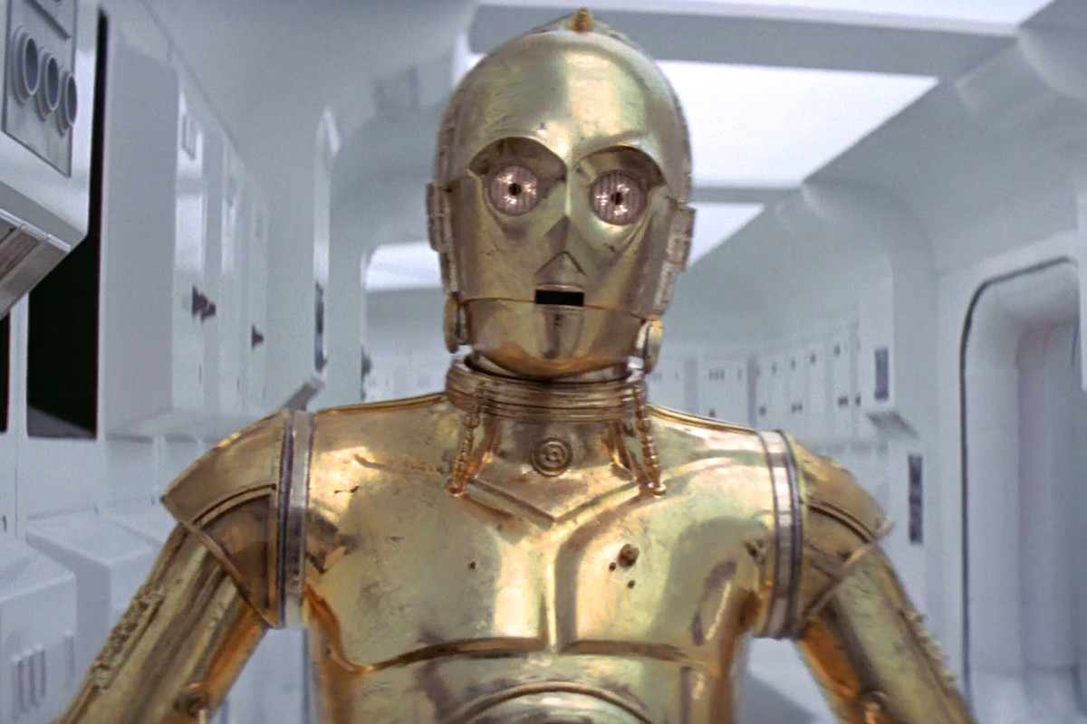 C-3PO faces the camera as a soldier rans behind him away from the action