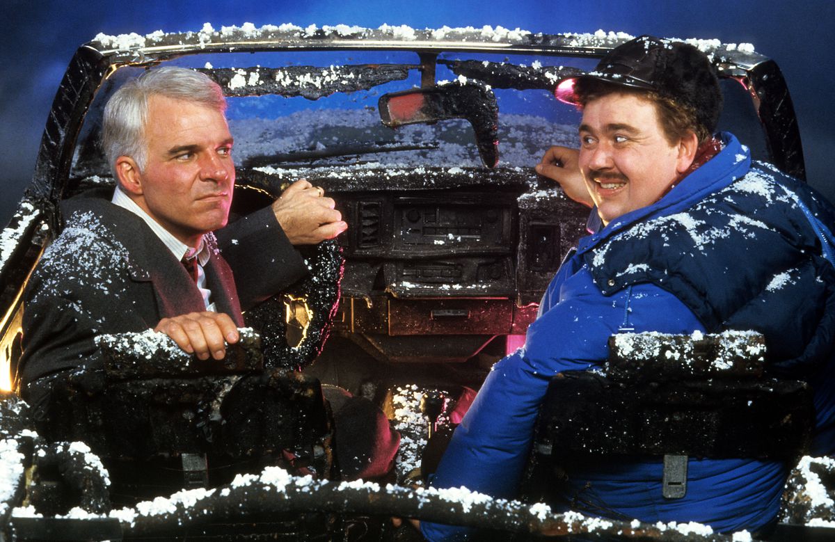 Steve Martin and John Candy sit in a destroyed car in a scene from the film 'Planes, Trains & Automobiles', 1987. (Photo by Paramount/Getty Images)