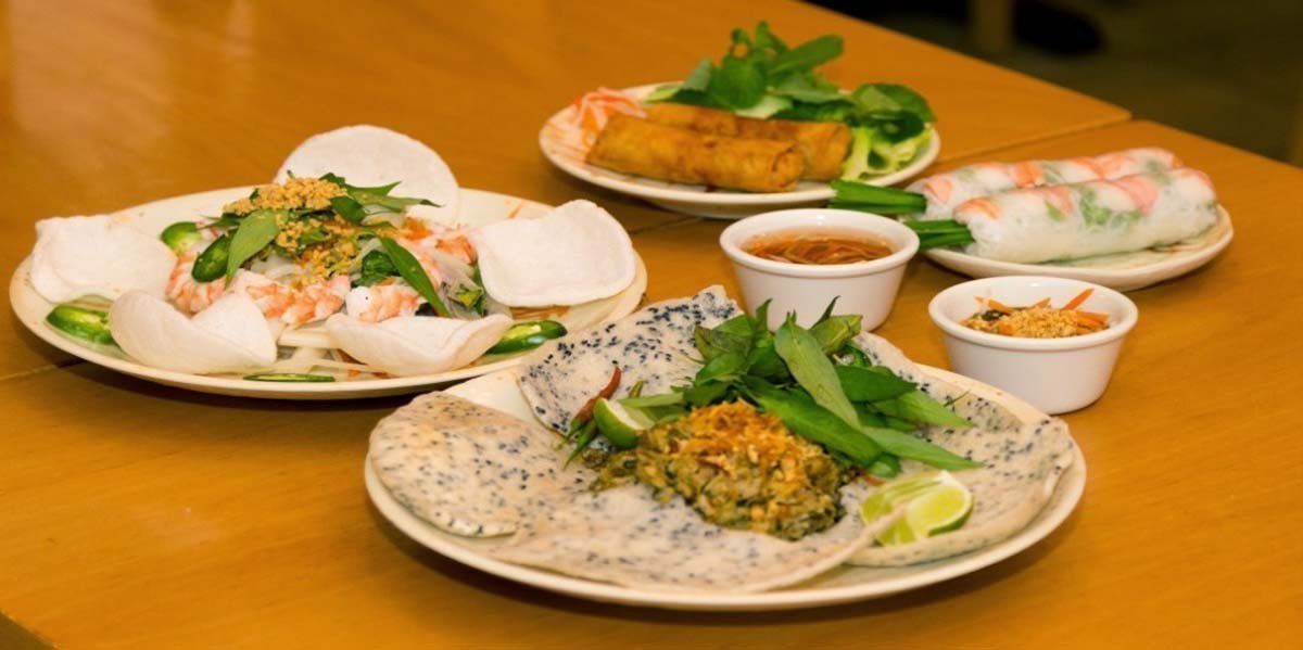 Four plates of Vietnamese dishes, including a dip with shrimp chips, spring rolls, summer rolls, and more
