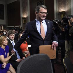 Ashton Carter, center, President Barack Obama's choice to head the Defense Department, reaches to hold the hand of his wife Stephanie as he arrives on Capitol Hill in Washington, Wednesday, Feb. 4, 2015,  to testify before the Senate Armed Services Committee hearing on his nomination to replace Chuck Hagel. Carter, who previously served as the No. 2 Pentagon official, is expected to easily win Senate confirmation but will face tough questions about Iraq and other issues. 