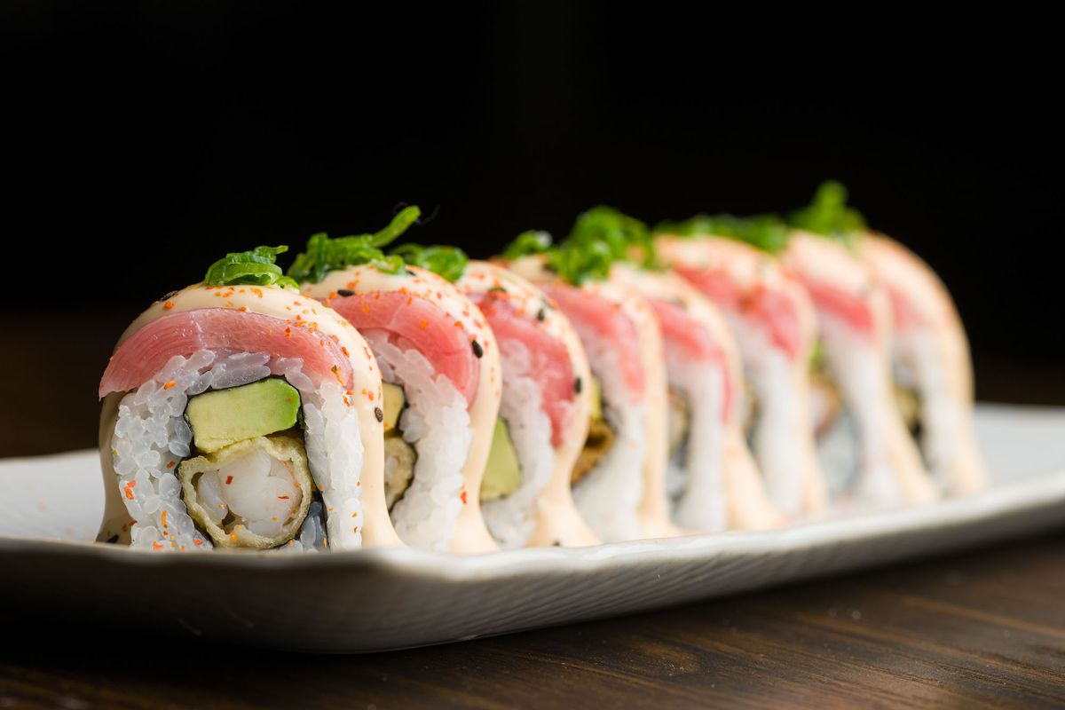 A long view of roll sushi with greens inside.