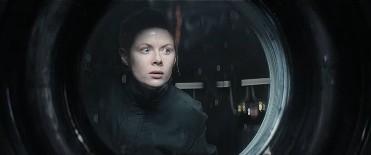 Maura (Emily Beecham) regarde par la fenêtre d'un vaisseau spatial, l'air perplexe en 1899.