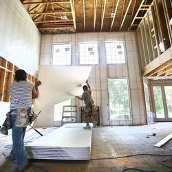 Workers install drywall in a room of a home as construction workers work to build homes in the Bellevue subdivision of Ivory Homes Monday, June 17, 2013, in Draper.