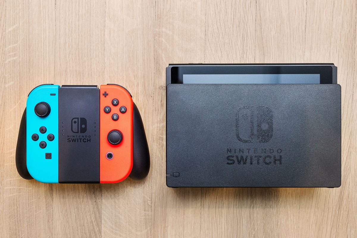 Nintendo Switch - Neon Red/Blue Joy-Cons in Joy-Con Grip next to Dock, all sitting on a wooden background
