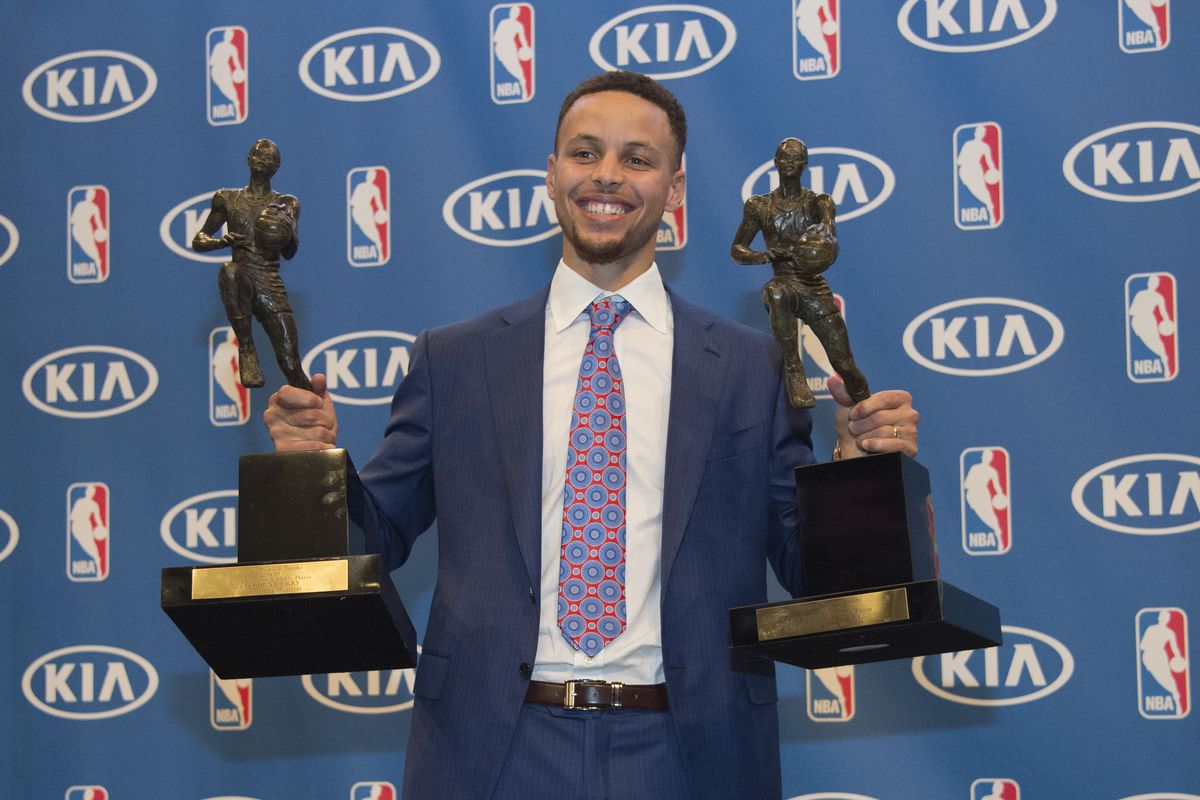 Steph Curry holding two MVP trophies