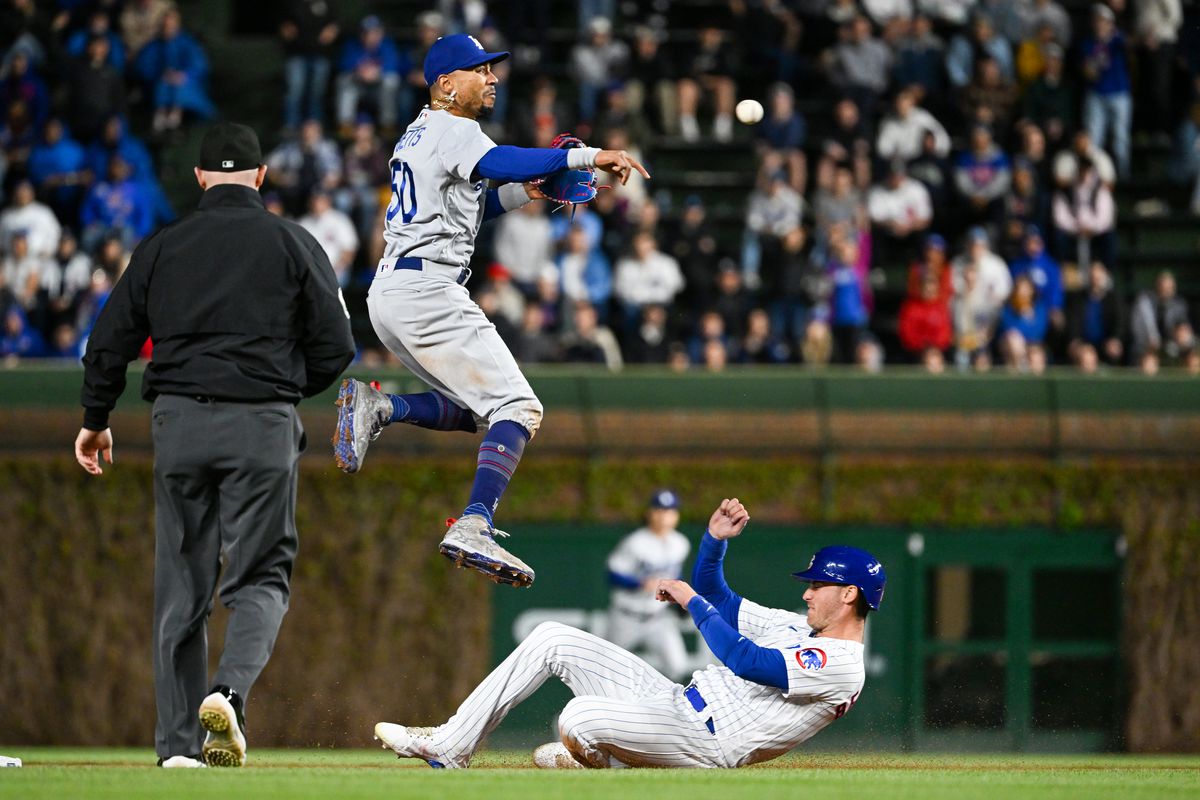 Mookie Betts of the Los Angeles Dodgers turns a double play in the eighth inning against Cody Bellinger of the Chicago Cubs at Wrigley Field on April 20, 2023 in Chicago, Illinois.