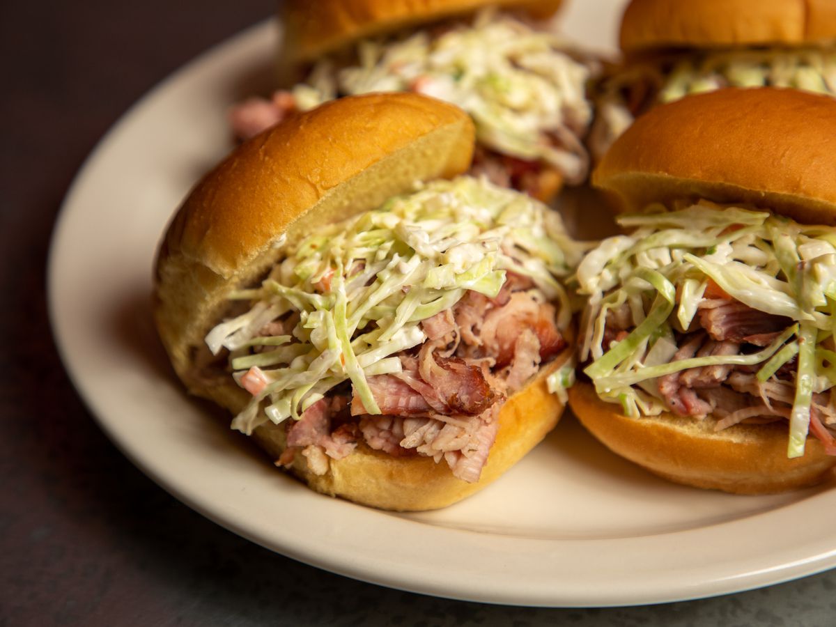 A white plate with subs stuffed with smoked meat and lettuce. 