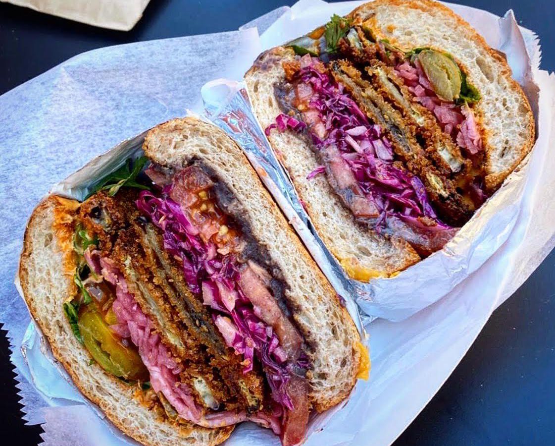 A torta milanesa at Guevara’s in Clinton Hill made with an eggplant cutlet, purple cabbage slaw, cherry peppers, avocado, refried beans, cilantro, and a mole-style “mayo.”