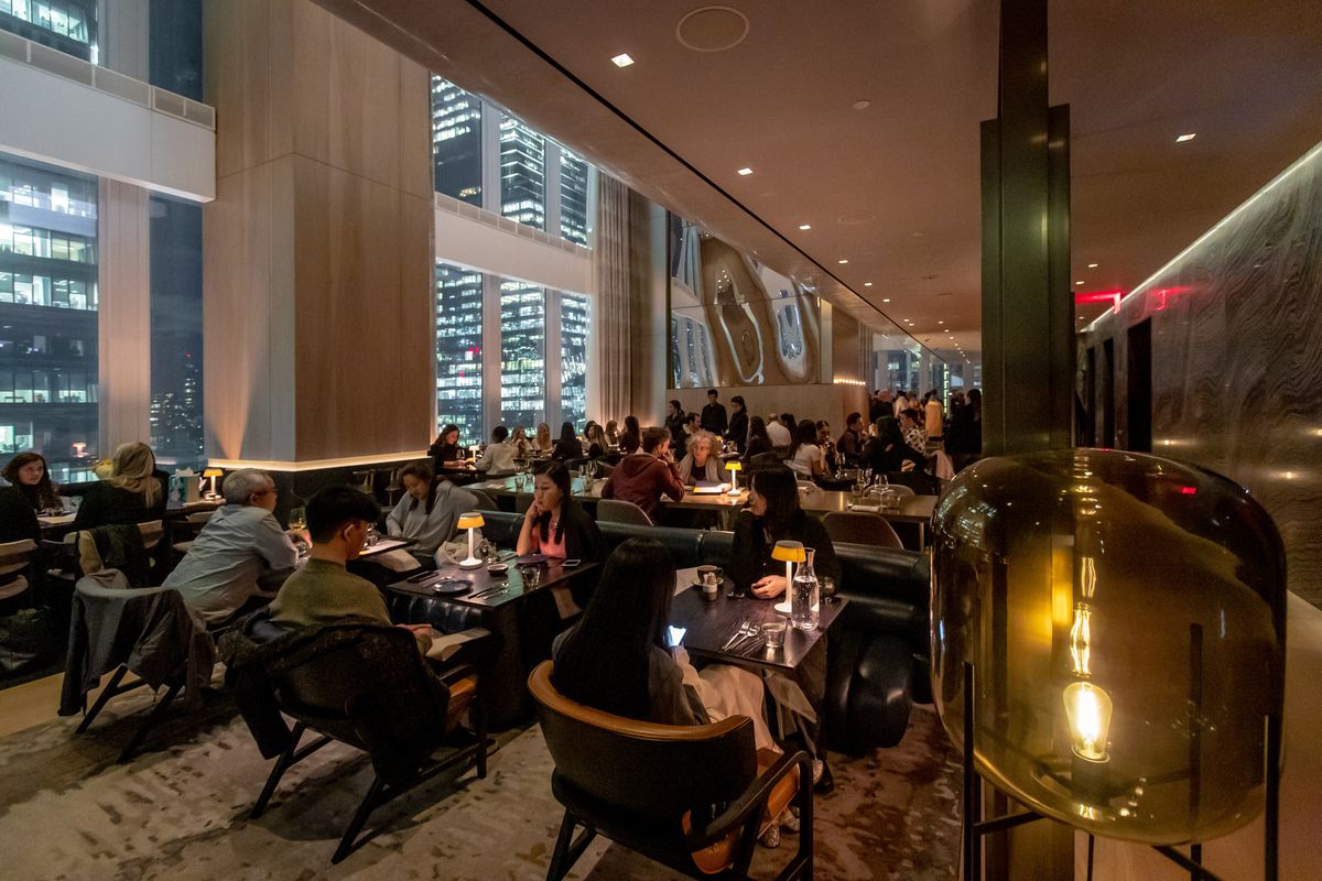 Patrons dine at tables at the Electric Lemon dining room, whose windows overlook Hudson Yards