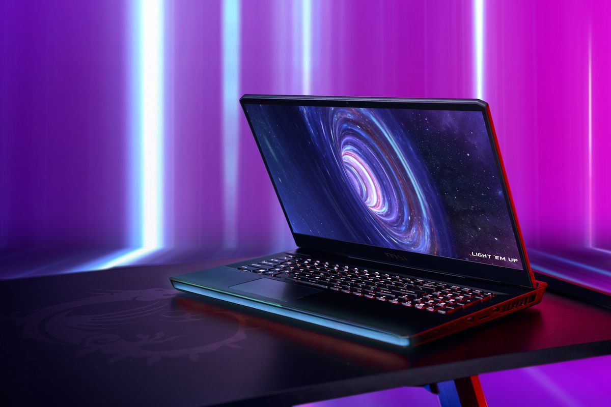 The MSI GE76 Raider open, angled to the left on a black table with a purple background. The LED strip and keyboard are illuminated. The screen displays a black hole with the slogan “Light ‘em up” in the bottom right corner.