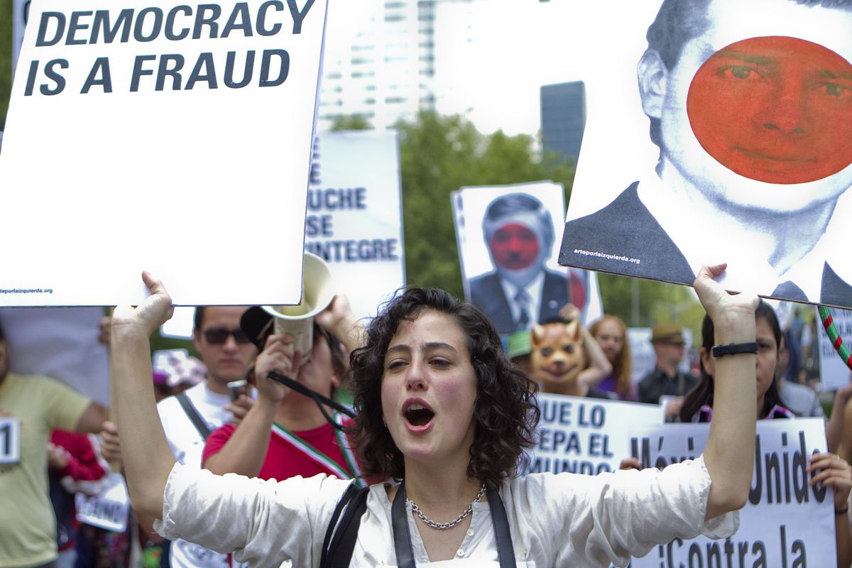 A woman in a protest holds a sign that reads, "Mexican Democracy is a Fraud."