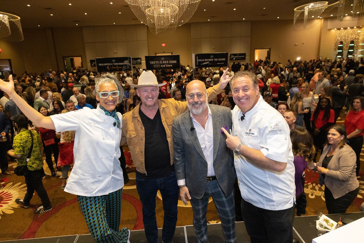 Carla Hall and Andrew Zimmern pose for a photo at an event center.