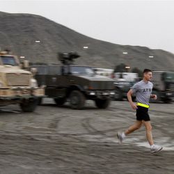 ADVANCE FOR USE FRIDAY, MAY 25, 2012 AND THEREAFTER - In this Wednesday, May 16, 2012 photo, U.S. Army Maj. George Kraehe runs past armored vehicles at his base in Kabul, Afghanistan. Most people run marathons to challenge themselves. Kraehe runs them to challenge others. As a member of the Tragedy Assistance Program for Survivors' Run & Remember Team, the New Mexico Army National Guard officer has participated in 20 races. And as he sweats his way along each 26.2-mile course, flapping against Kraehe's back is the laminated photograph of a service member who has died in what has become the U.S.'s longest war. (AP Photo/Ahmad Jamshid)