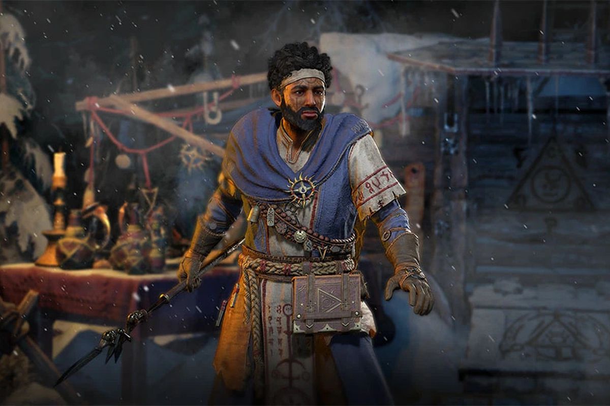 A man stands in town in Diablo 4, holding a staff and wearing a blue scarf