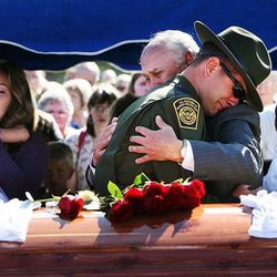 Border Patrol Agent Joel Ivie, brother of U.S. Border Patrol Agent Nicholas J. Ivie hugs his father, Doug Ivie, at the end of a graveside ceremony for Nicholas J. Ivie in Spanish Fork, Thursday, Oct. 11, 2012. At back left are Christy Ivie, wife of Nicholas J. Ivie, and her daughter Raigan. Agent Nicholas J. Ivie died when fatally wounded in the line of duty.
