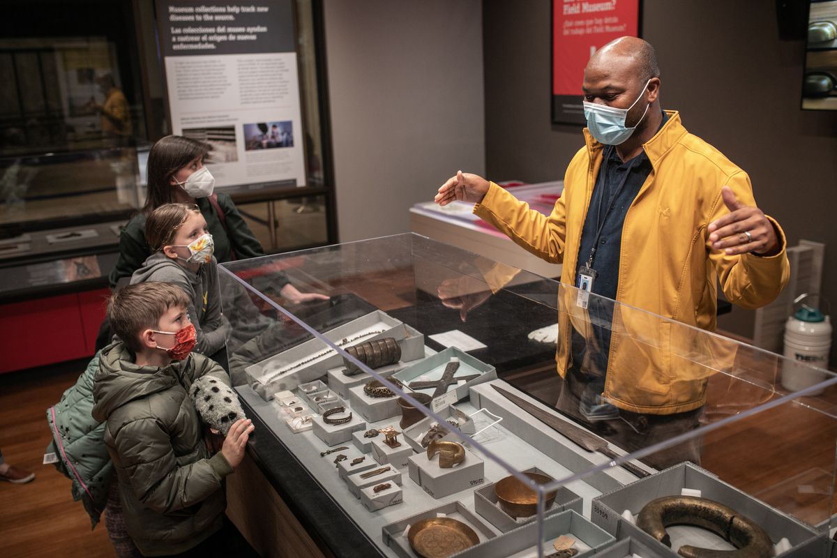 The Field Museum’s new assistant curator of African anthropology talks to museum visitors Maureen Haines and her kids Nicholas and Evie about African metalwork with the museum’s collection.