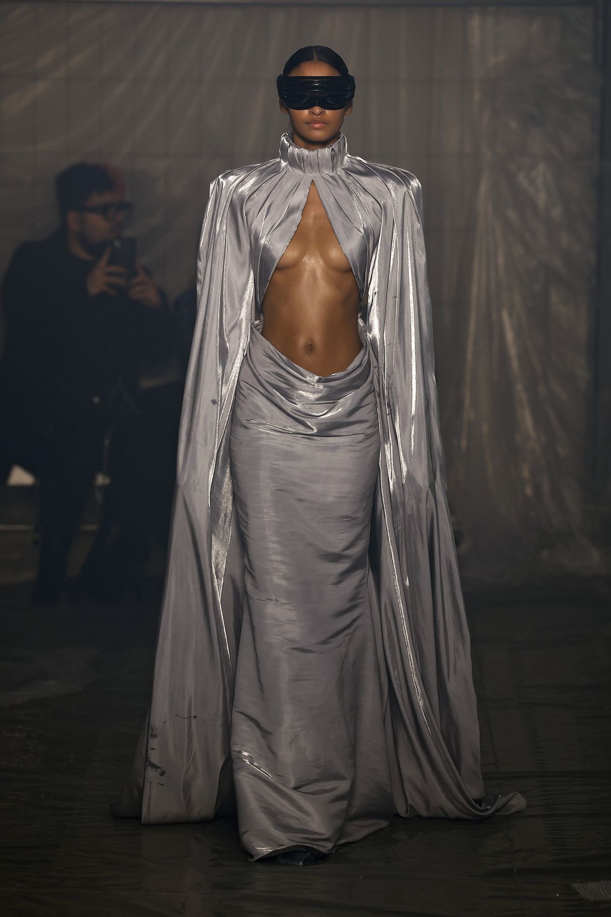 A model wearing a flowing gray dress with her midriff exposed walks the runway at the Han Kjobenhavn fashion show at Milan Fashion Week.