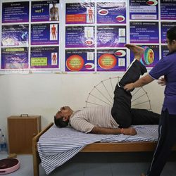In this Thursday, June 11, 2015, photo, a yoga instructor, right, evaluates a patient at Vivekananda Yoga Anusandhana Samsthana University hospital in Jigani, near Bangalore, India. There are no reliable estimates of how many people regularly practice yoga in India, though the number is certainly in the millions. Sunday, June 21, 2015, marks the first International Yoga Day, which the government of Prime Minister Narendra Modi is marking with a massive outdoor New Delhi gathering. 