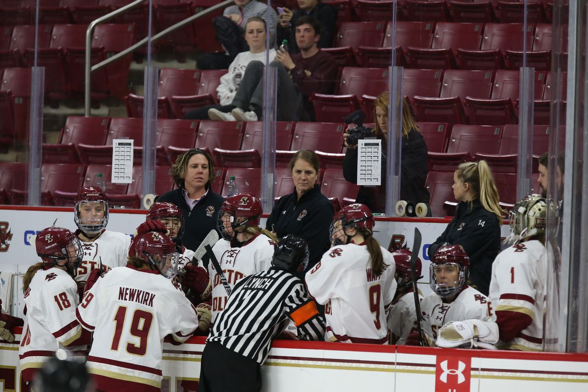 Boston College players gather around coaches Katie Crowley and Courtney Kennedy on the bench during a game.