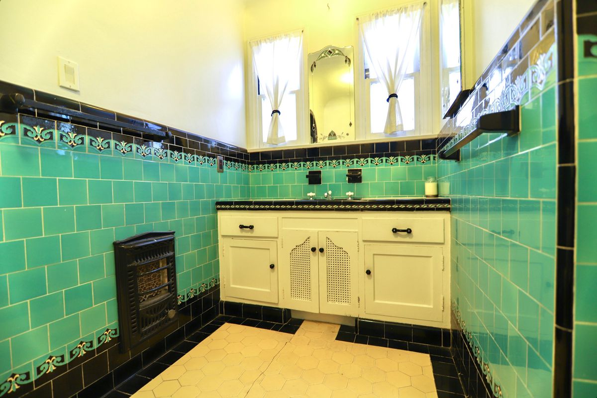 Bathroom with teal tiles and white cabinets. 