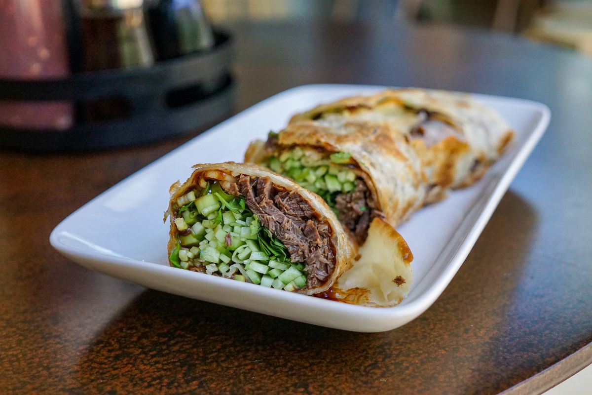 A close up side shot of a Taiwanese beef roll with shredded beef and greens.