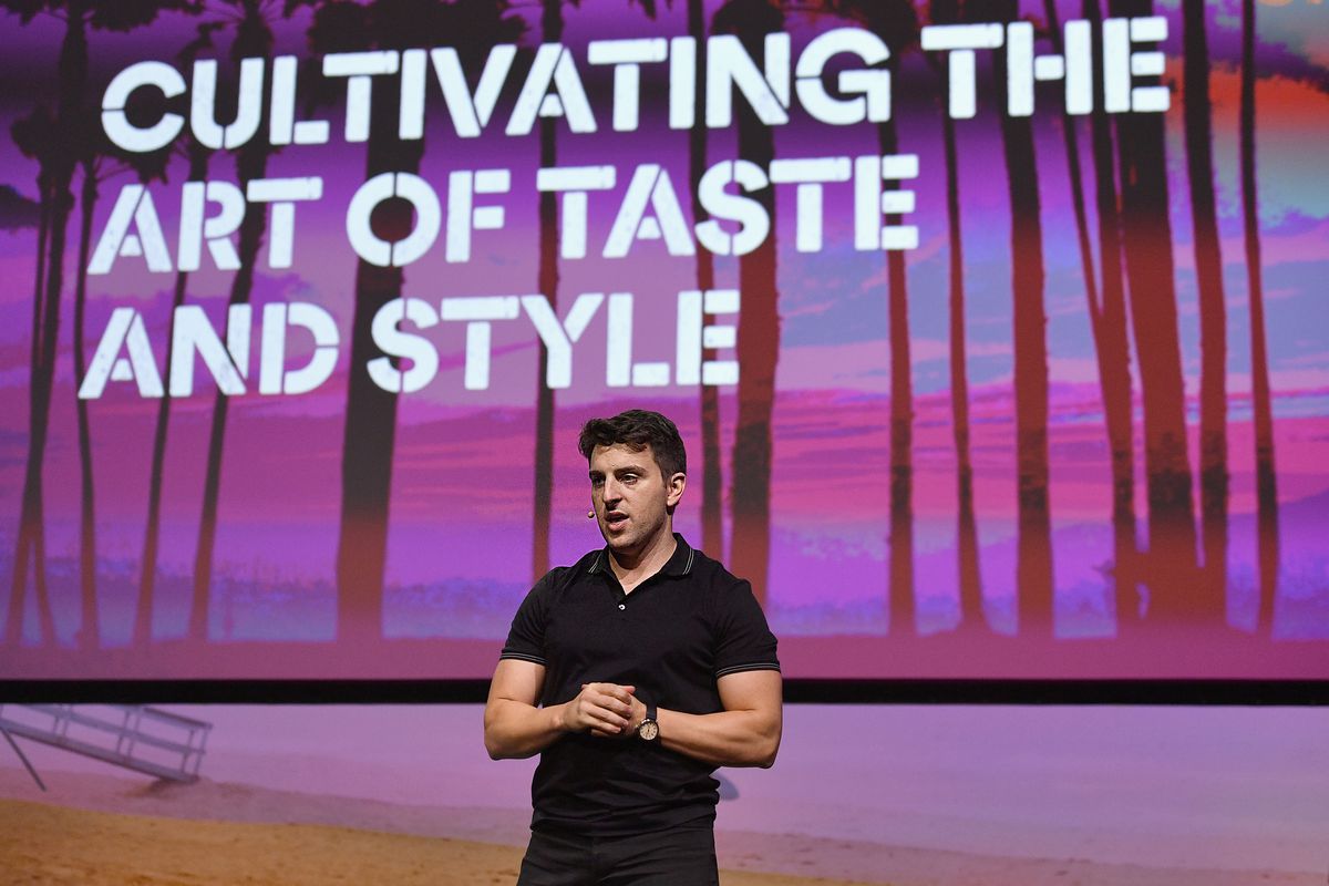 Airbnb CEO Brian Chesky onstage in front of a sign reading, “Cultivating the art of taste and style.”