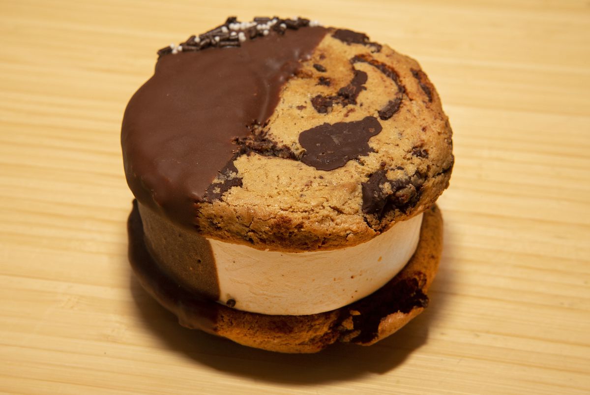 A chocolate-dipped ice cream sandwich between two chocolate chip cookies