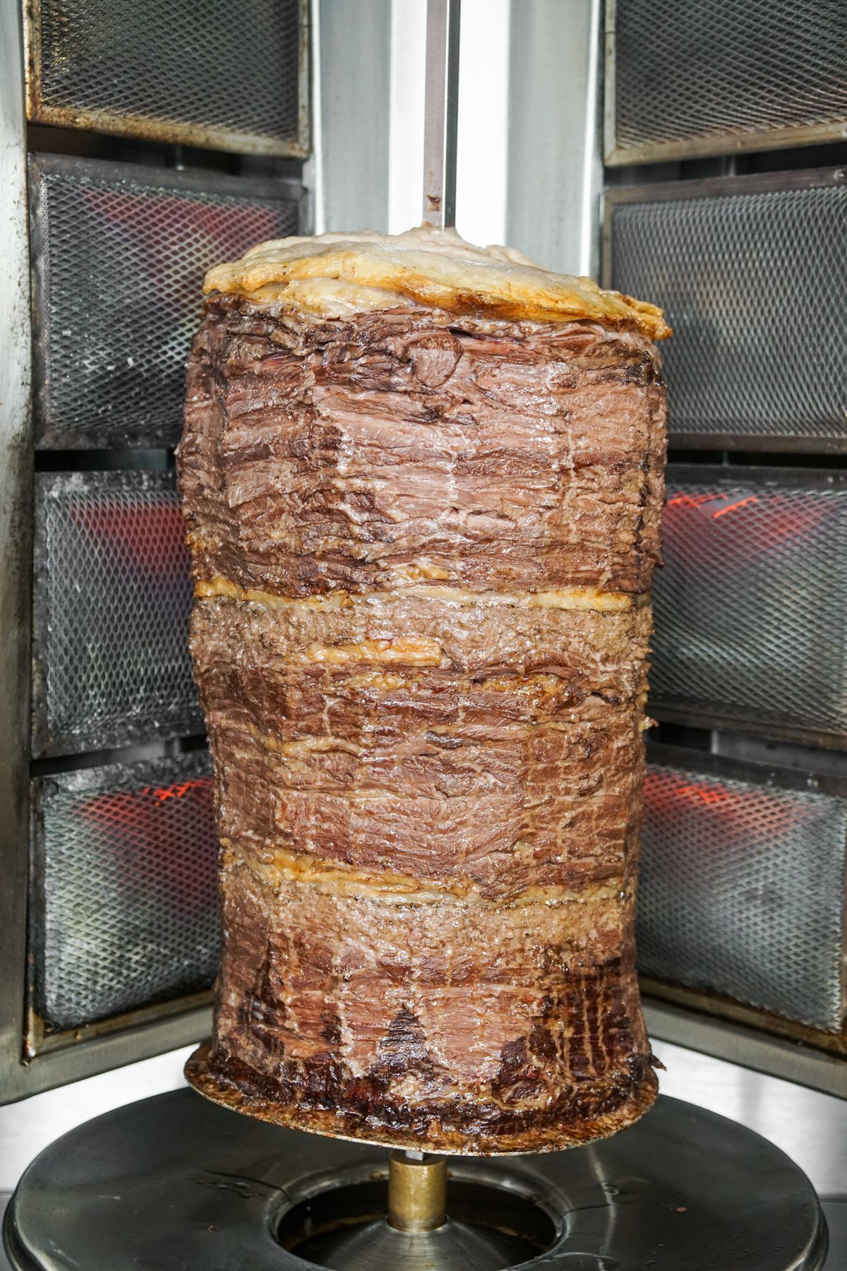 A vertical shawarma spit inside of a metal heater at an LA restaurant.
