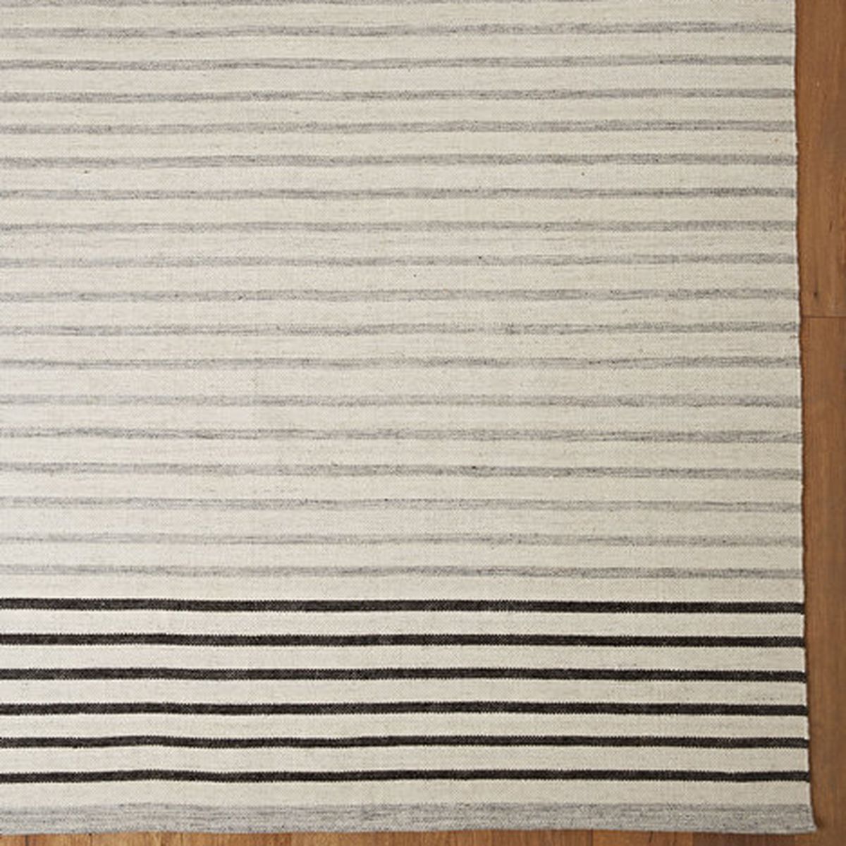 Rectangular rug with mostly gray stripes and a few black stripes near one edge. 