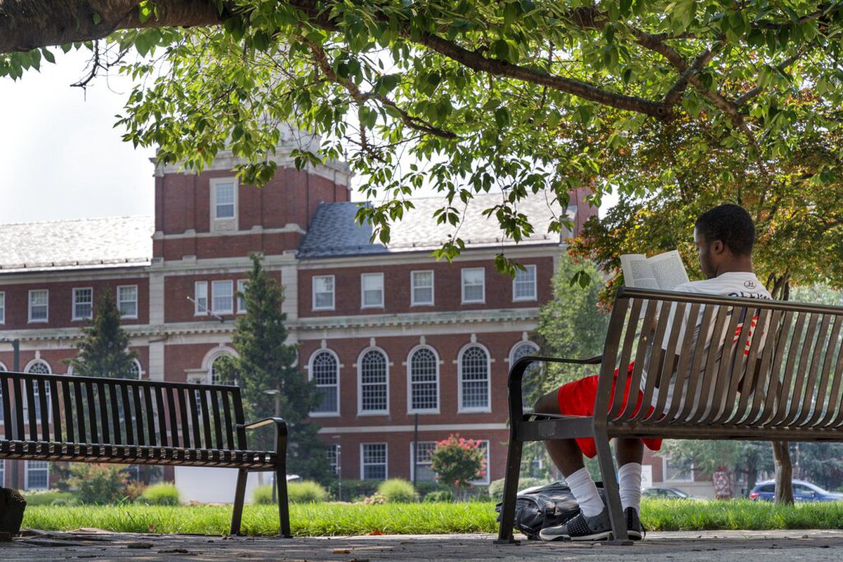 A young man reads on Howard University’s campus.