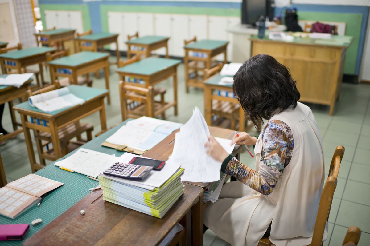A teacher grades papers in a classroom.