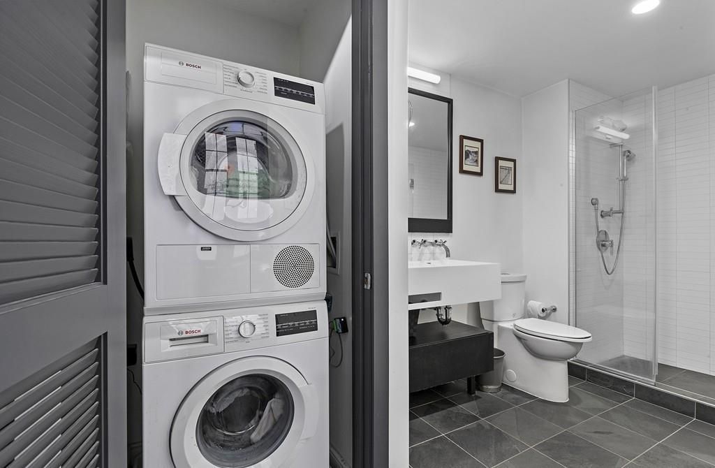 A large bathroom with a stacked washer-dryer next to the toilet. 