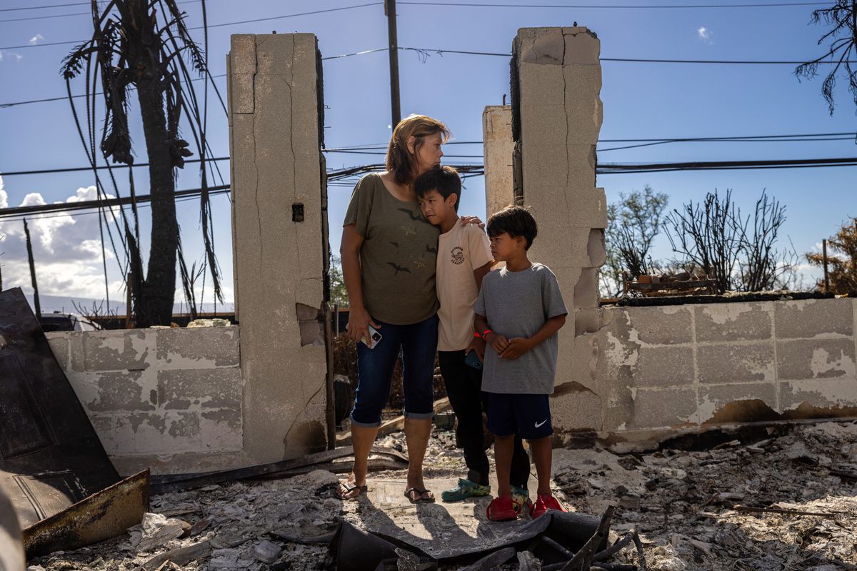 Val Casco and her grandsons Hawea Casco, 9, and Hanuola Casco, 6, stand at the entrance to her home, which was destroyed in the August 8 wildfires in Lahaina, Hawaii, on August 24, 2023.