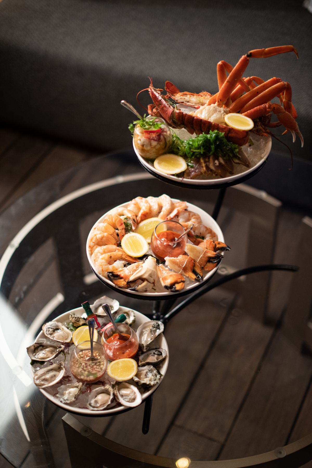 A trio of seafood plates on a tower at a table at a cool lounge.