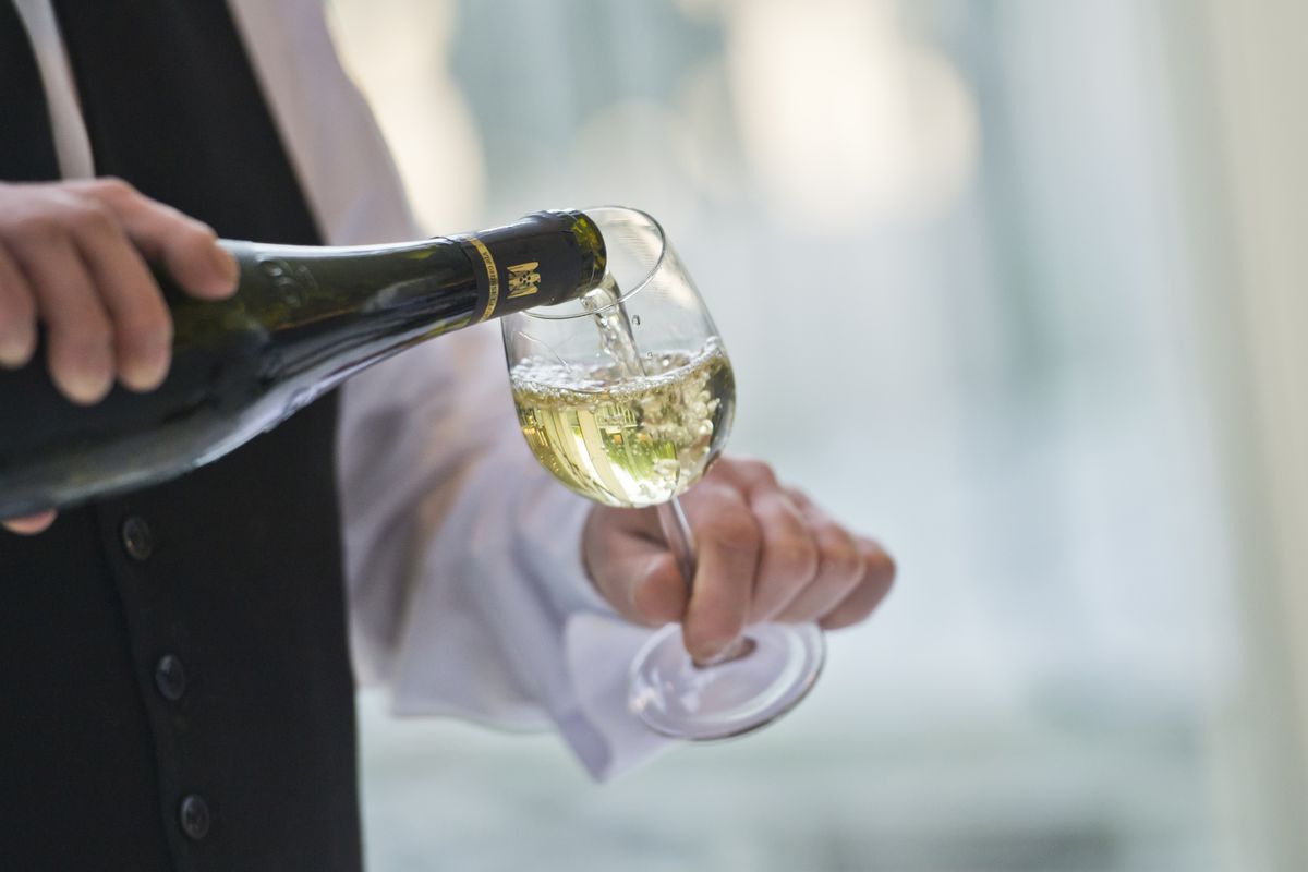 A Waiter pours a glass of white wine...