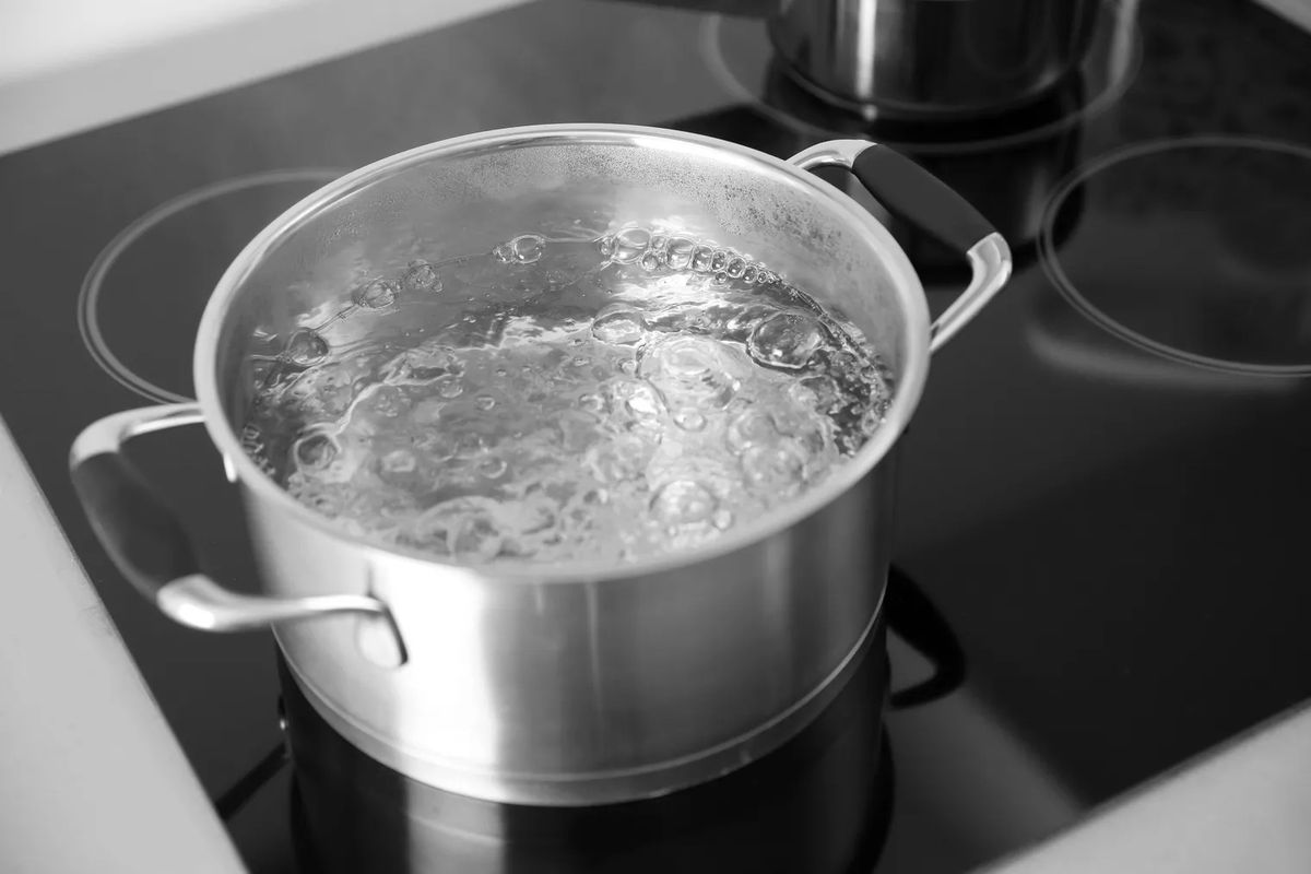 A bot of boiling water on a stove.