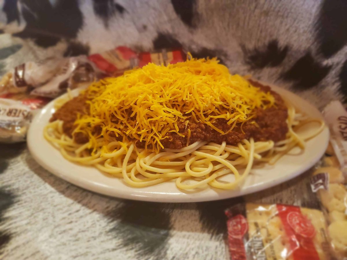 Chili on spaghetti topped with shredded cheese.