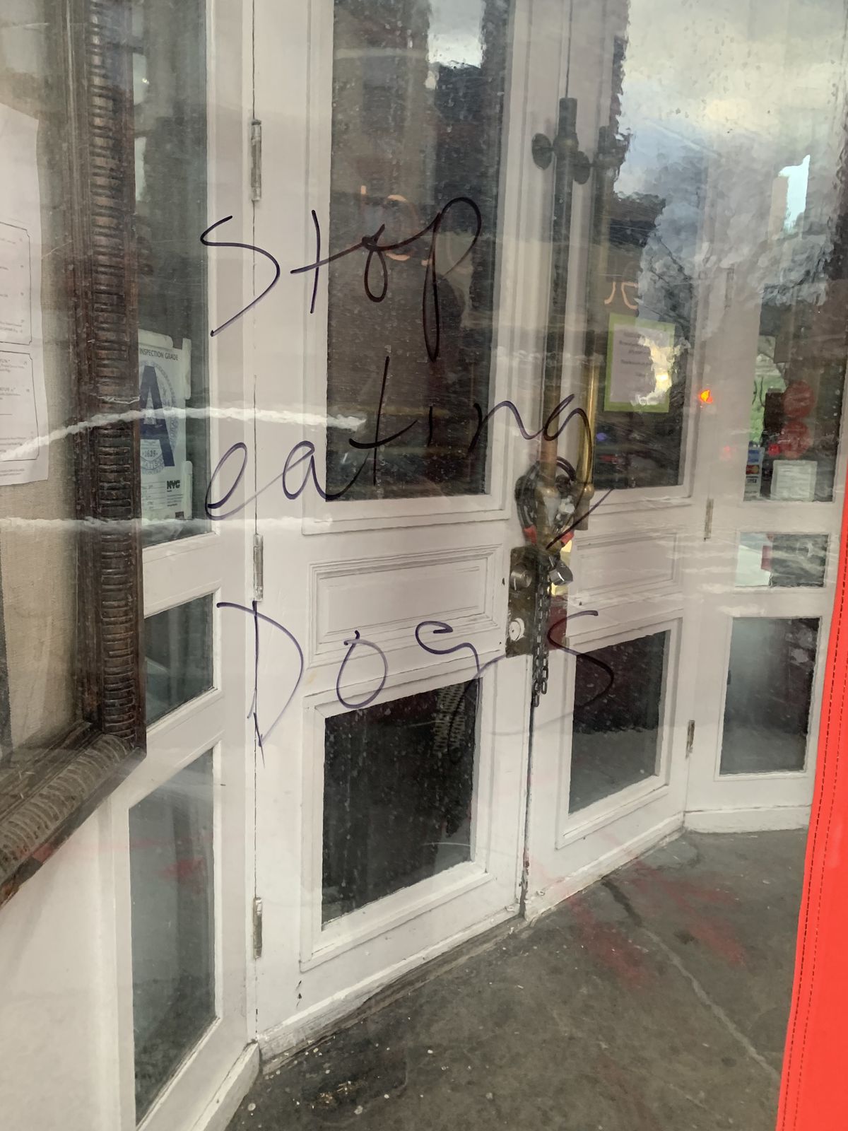 Racist graffiti spelling out “stop eating dogs” scrawled on the front of Jeju Noodle Bar’s winter vestibule