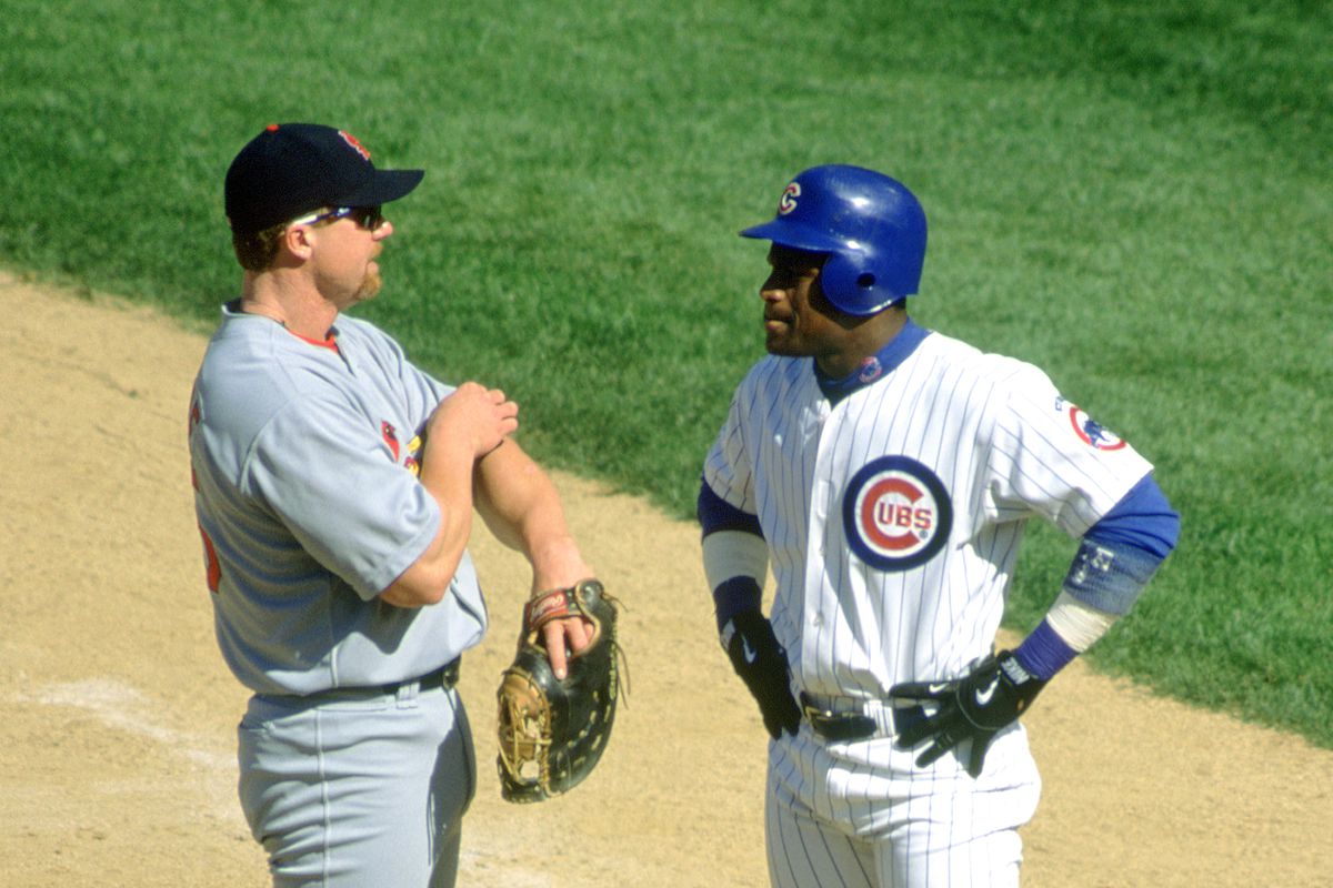 Mark McGwire #25 of the St. Louis Cardinals talks with Sammy Sosa #21 of the Chicago Cubs during a game at Wrigley Field circa 1998 in Chicago, Illinois.