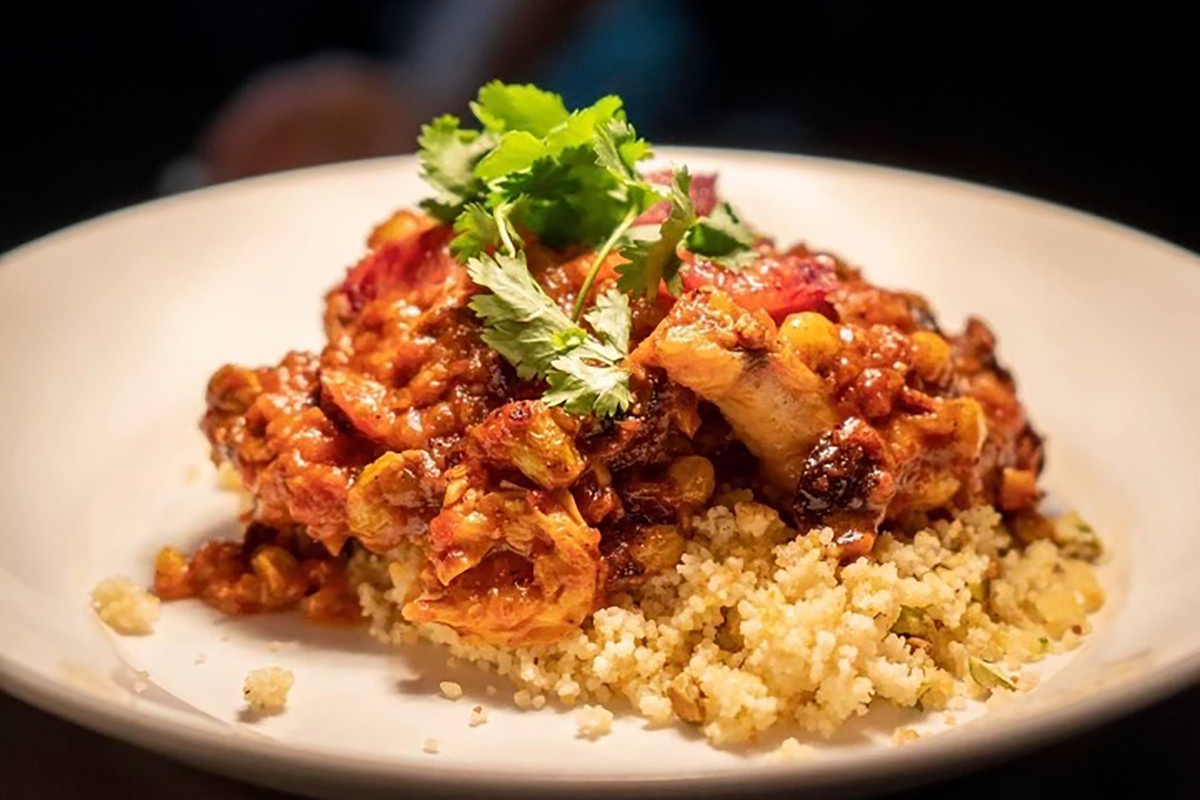 A plate of Moroccan chicken on a bed of pistachio couscous at Nova in Dallas.