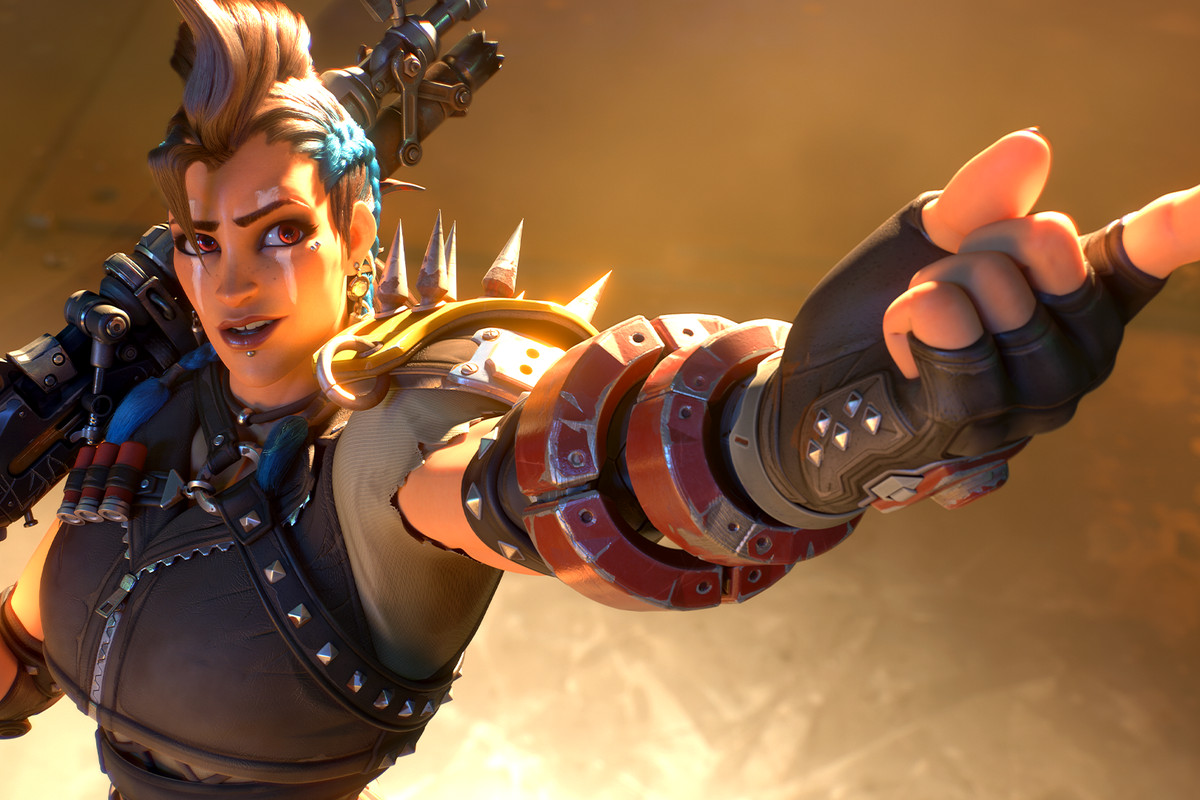 Screenshot from Overwatch 2 Junker Queen cinematic featuring the Junker Queen character with a brown mohawk and blue braids wearing ripped up post-apocalyptic body armor pointing off screen.
