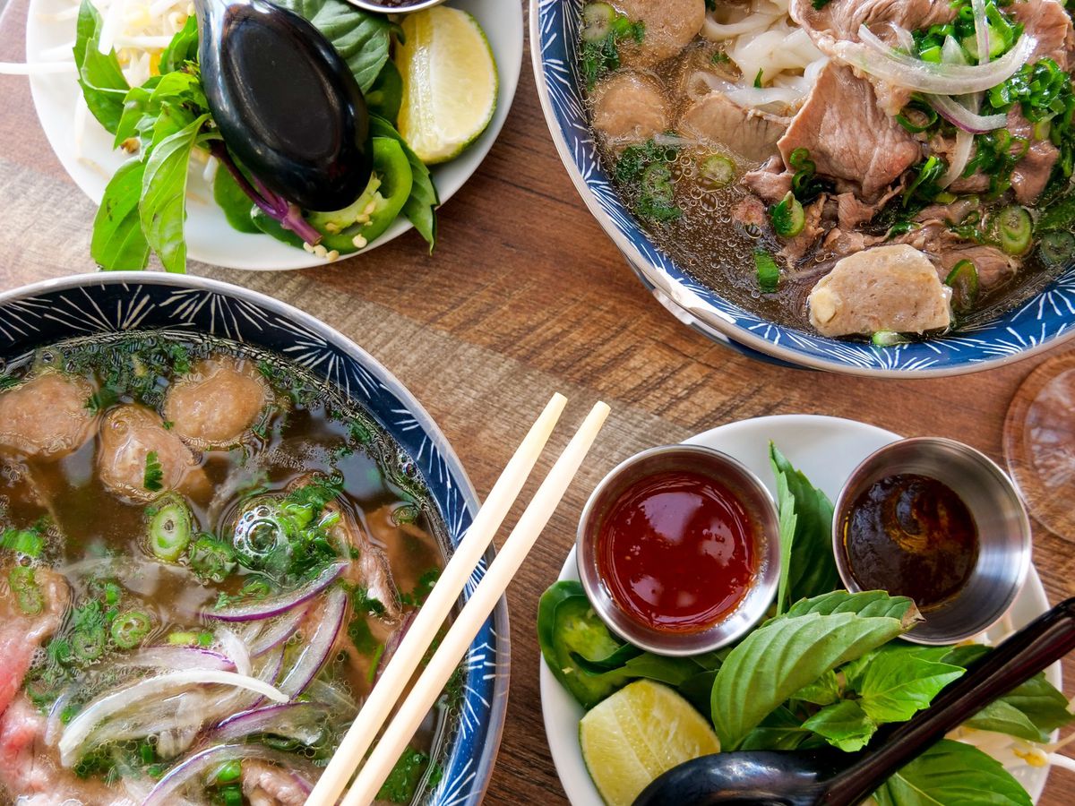 Bowls of pho with fixing and chopsticks.