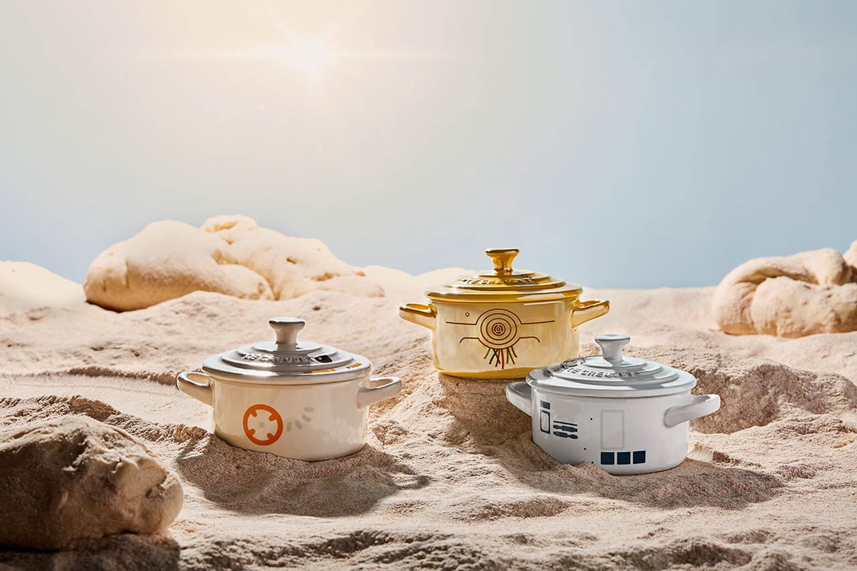 Three Star Wars-themed Le Creuset pots in a sand-and-rock landscape.
