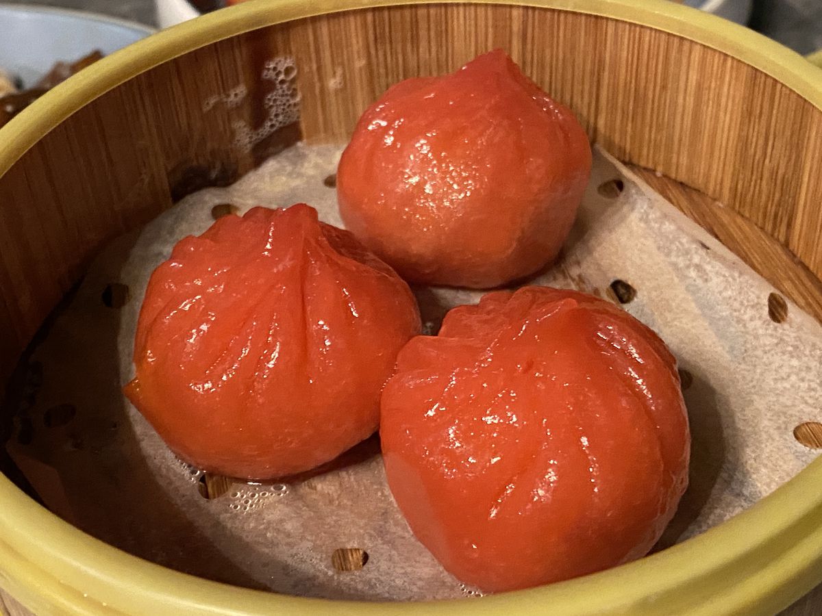 Three bright orange dumplings in a steamer basket.