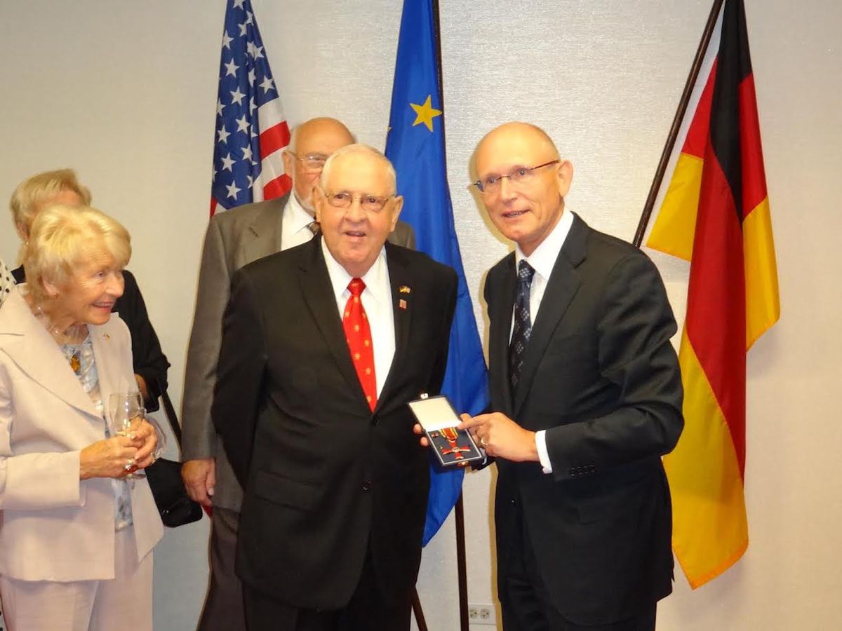 Ray Lotter receives Germany’s order of merit from Herbert Quelle, Chicago’s former German consul general as his wife Dorothea Lotter looks on.