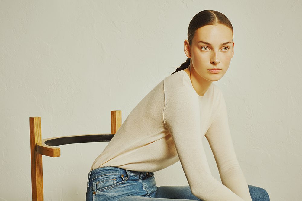 a model with a braid wears a simple sweater and jeans