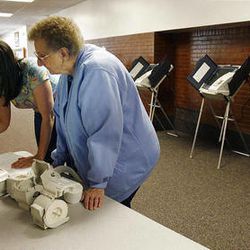 Barbara Grundvig, left, Malinda Bills and Beverly Noorda read instructions for setting up voting machines at Sandy Elementary School in Sandy, Monday, Nov. 7, 2011.