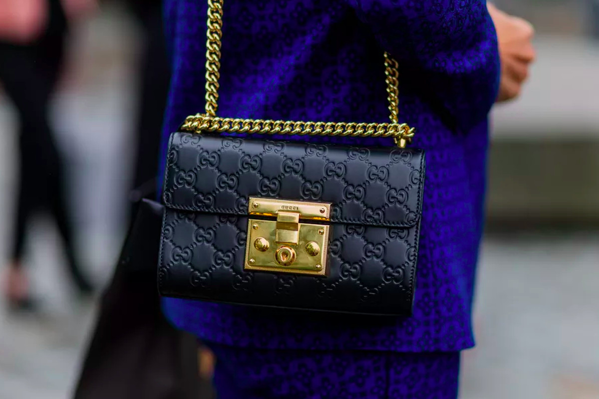 A close-up of a black Gucci shoulder bag with gold detail.