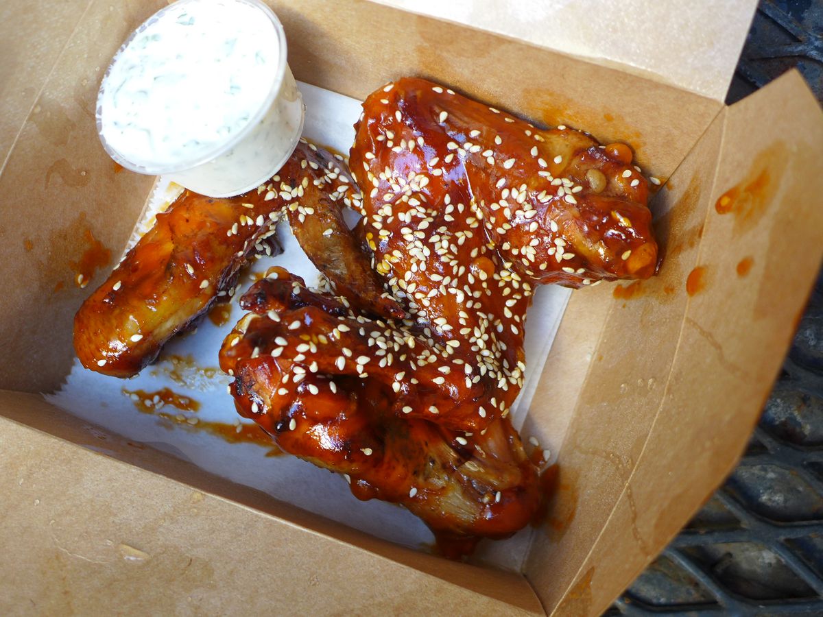 Three whole, three section wings in a cardboard box with a green-flecked white dressing.